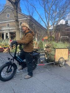 Tree Riders NYC crew member carrying a Christmas tree at the East Village stand